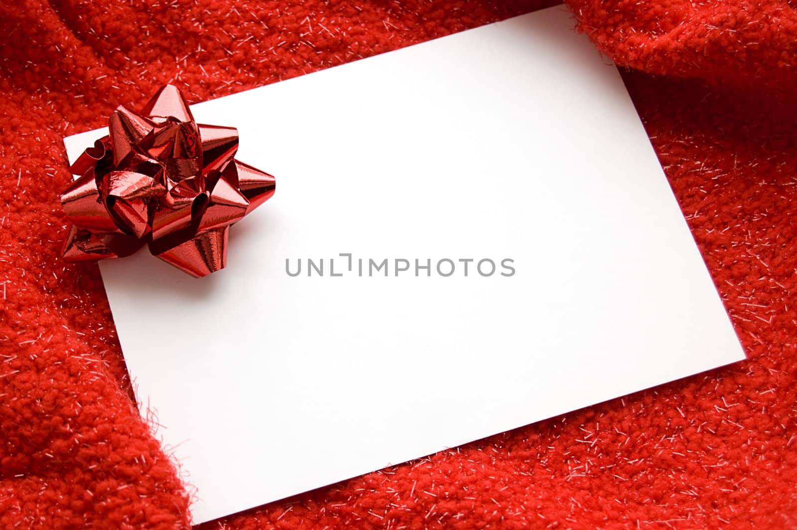 White blank note with red ribbon bow on red background