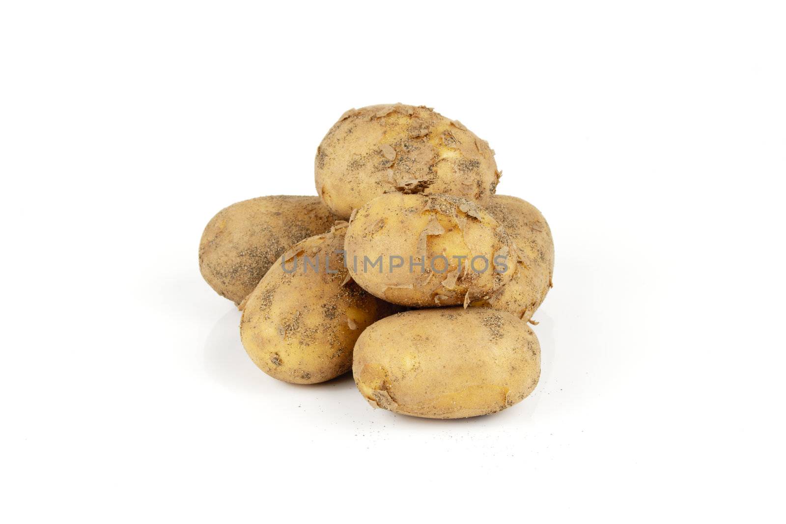Small pile of brown unpeeled potatoes on a reflective white background