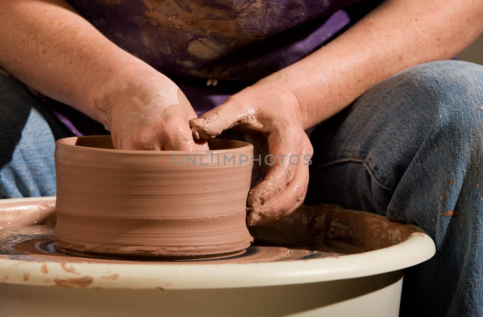 Potter shaping clay on a turning wheel