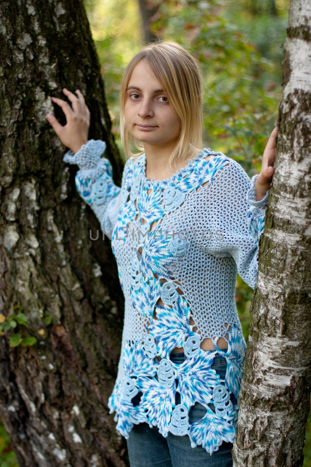 sunburned girl in blue pullover between two birches
