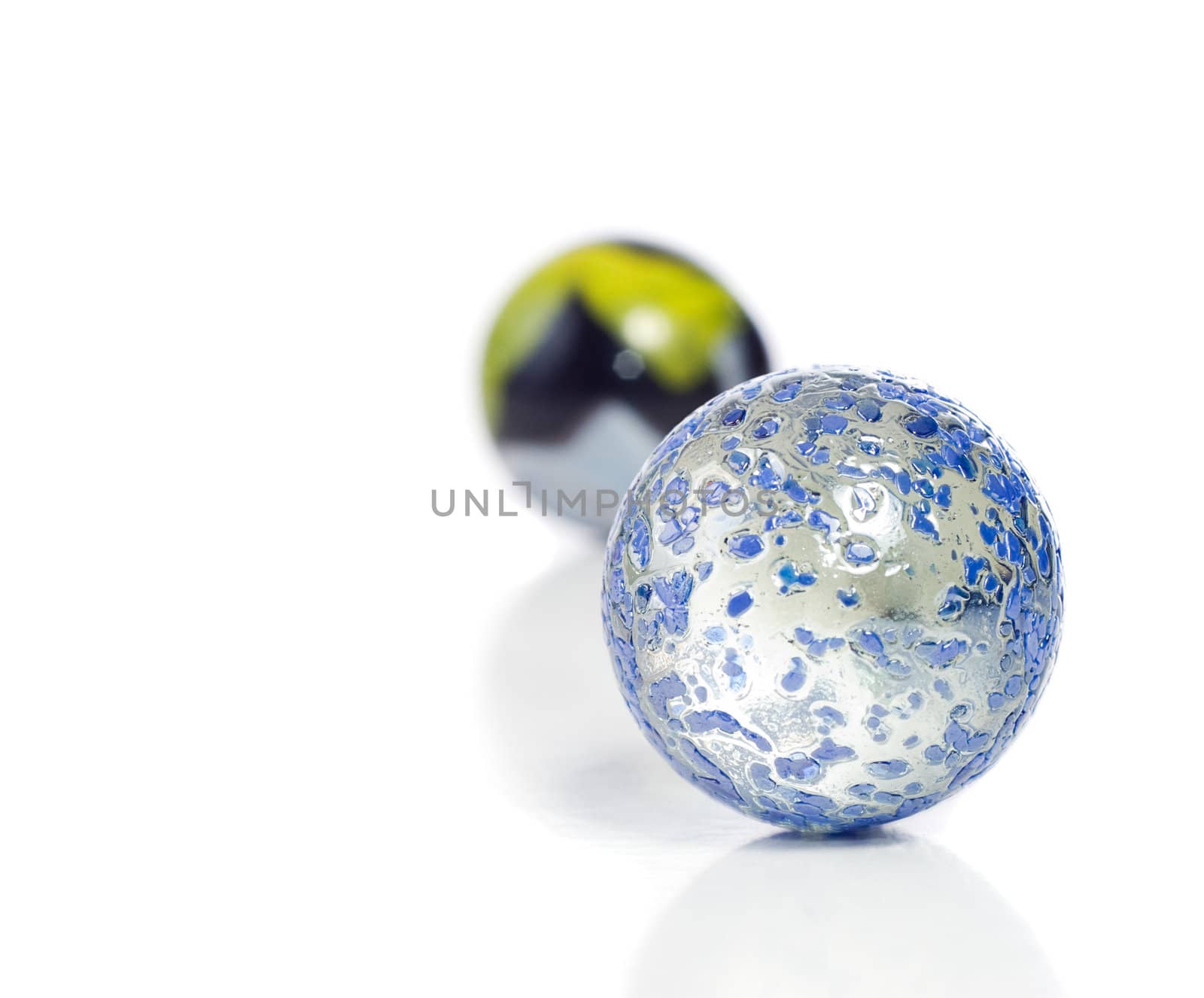 Closeup view of a game of marbles shot on a white background with a slight reflection on the surface