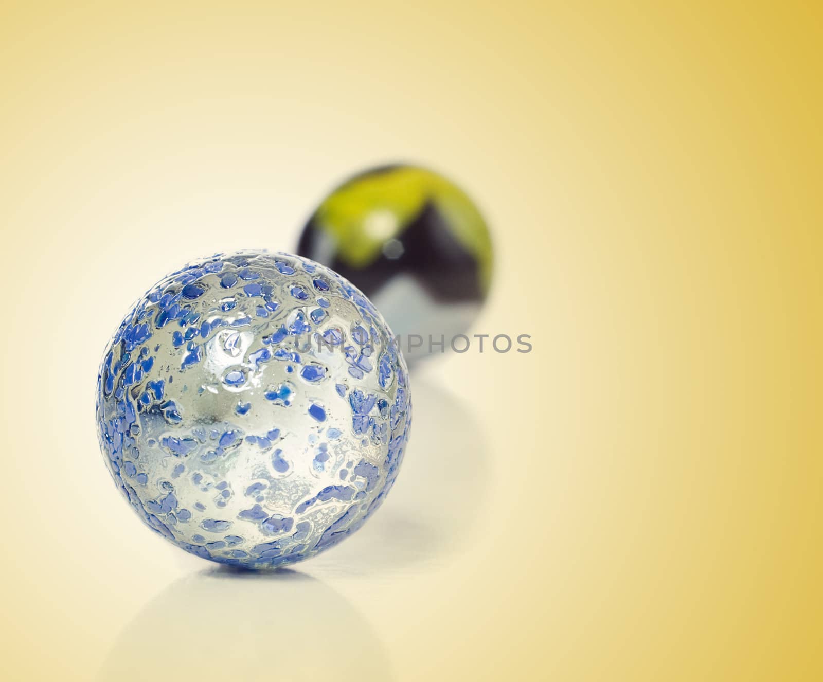 Closeup view of a game of marbles shot on a white background with a slight reflection on the surface