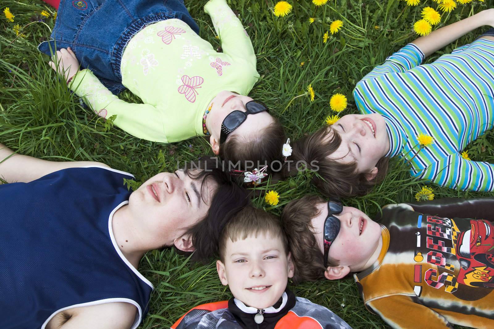 Children wearing sunglasses resting on the grass