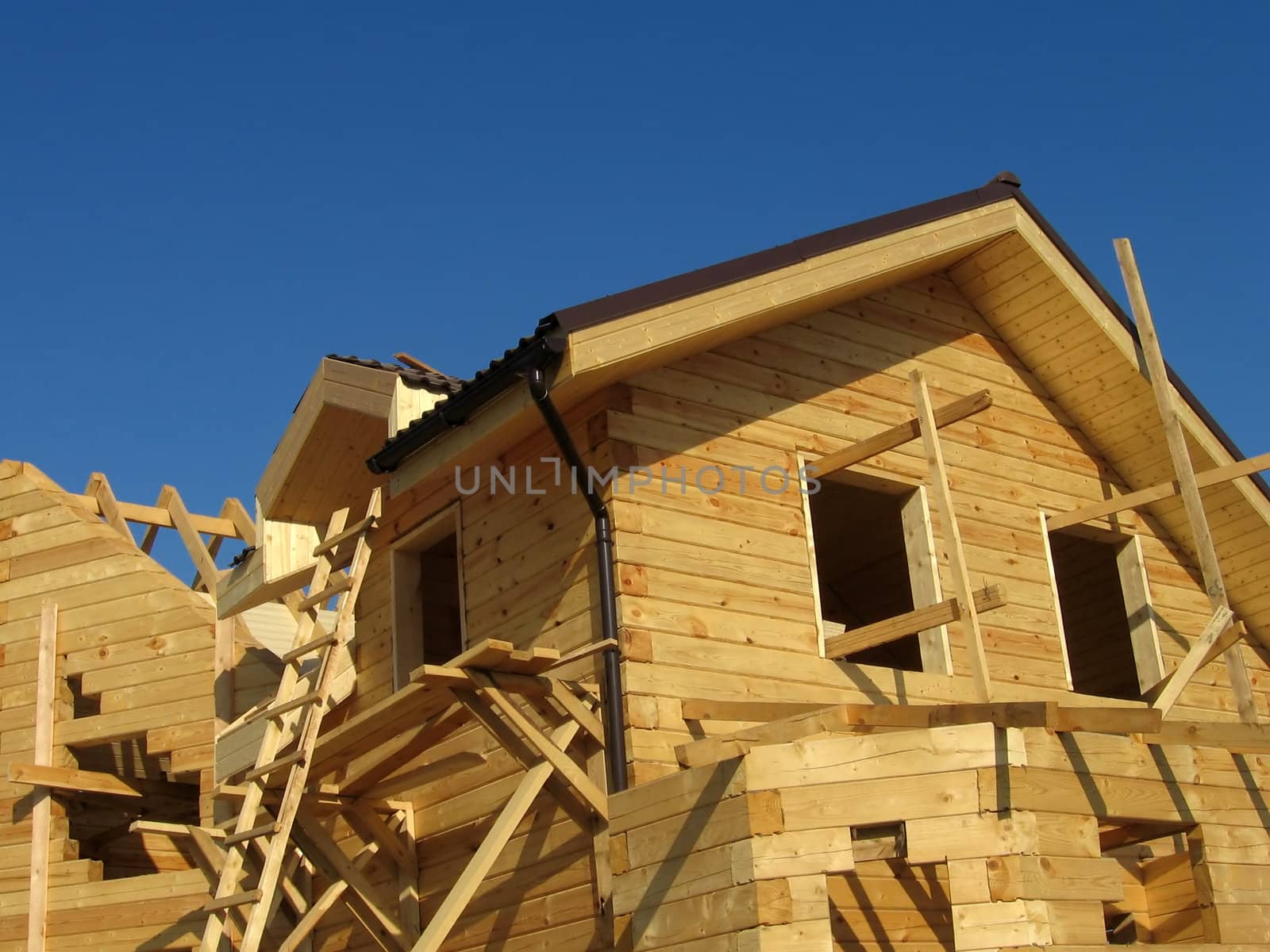 The new house creating from wood bars on a background of blue sky