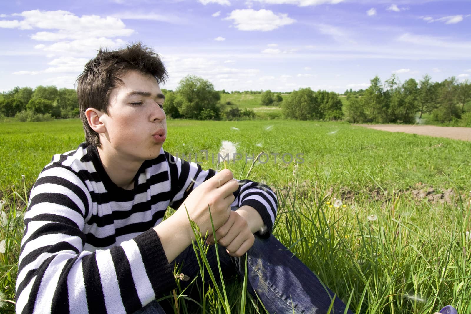 Portrait of teenager blowing a dandelion