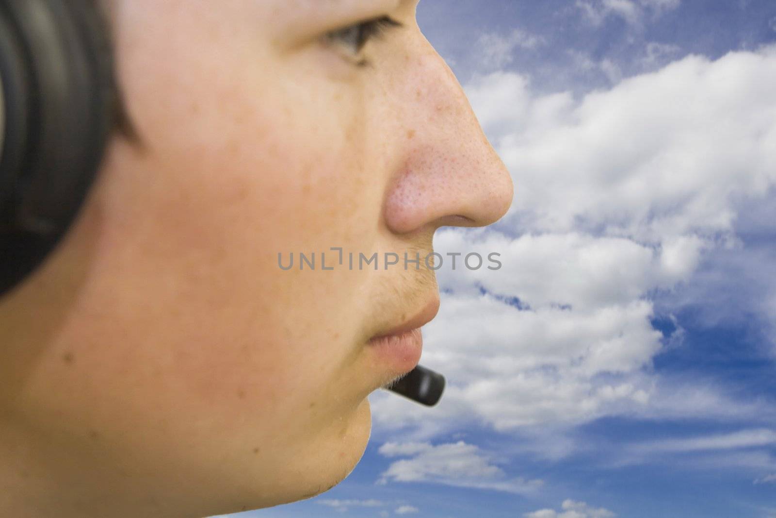 Travel-agency manager with headphones against blue and cloudy sky. Focus to mouth