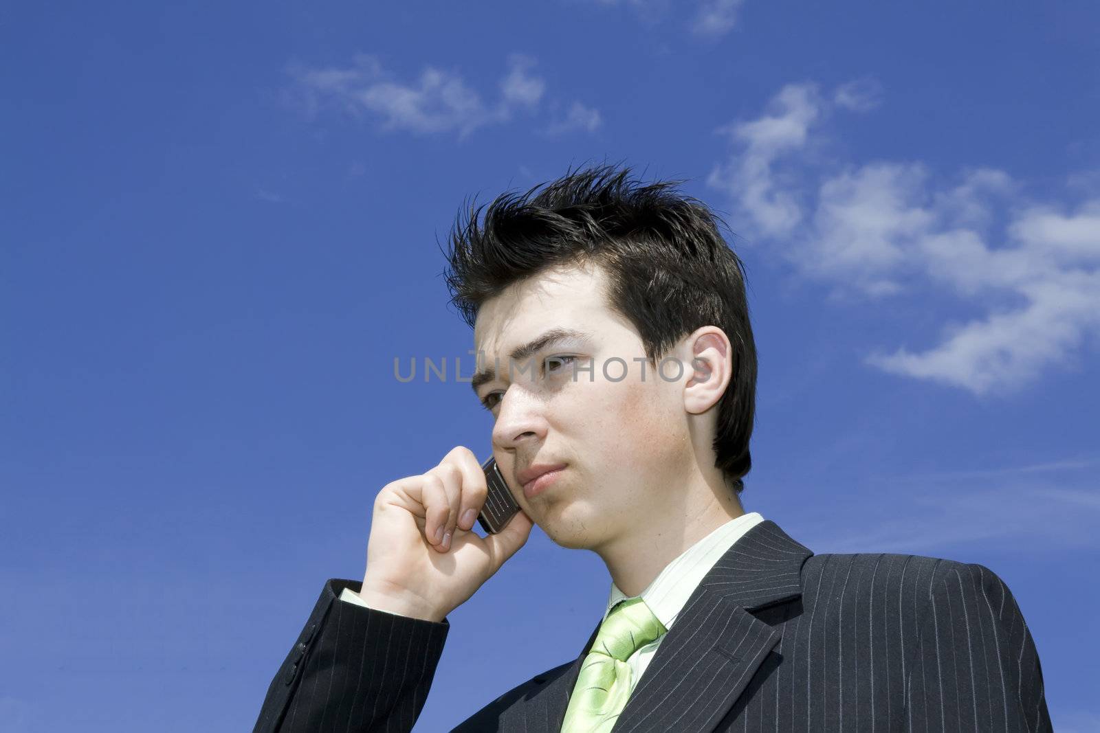 Businessman talking with mobile against blue sky background. Copyspace