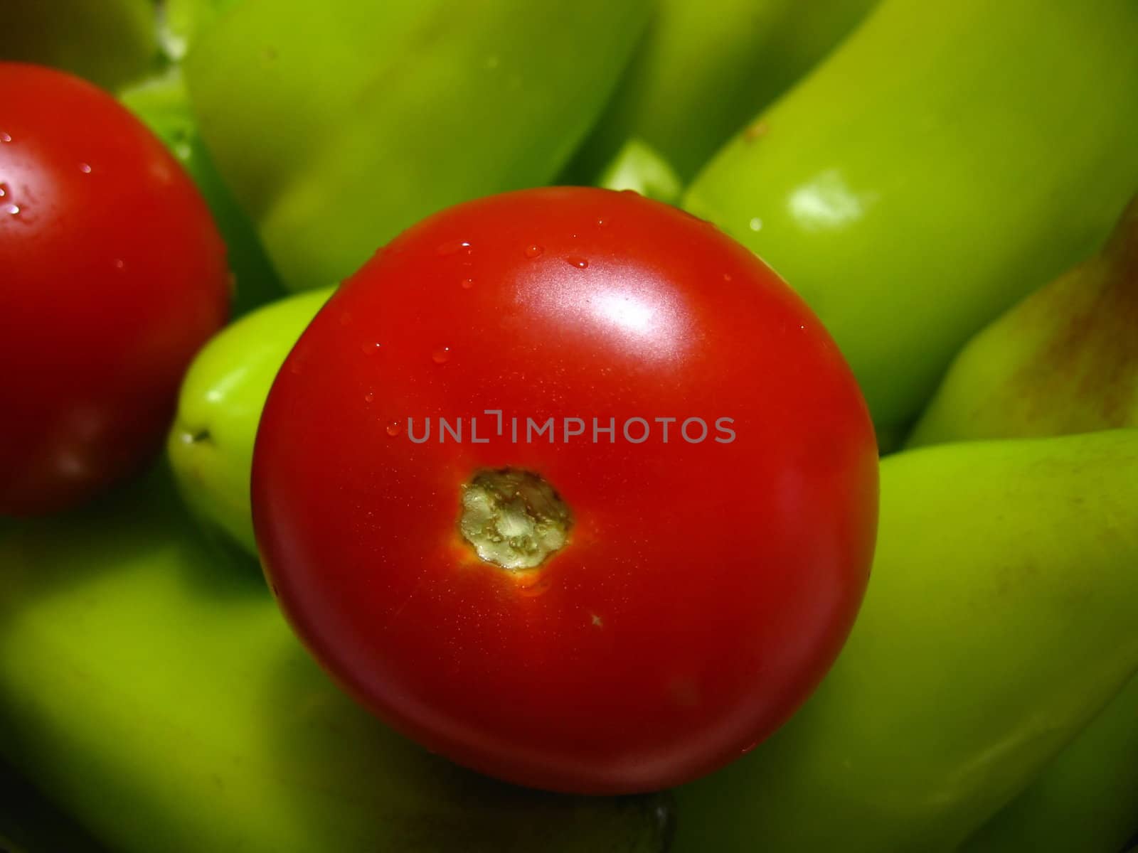Red tomato on a background of green peppers 