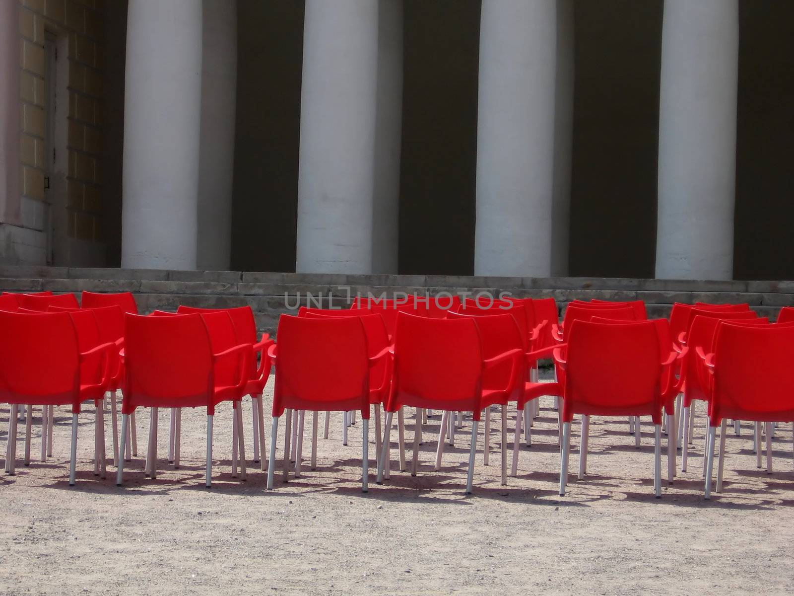 Red plastic chairs near a stage before a concert