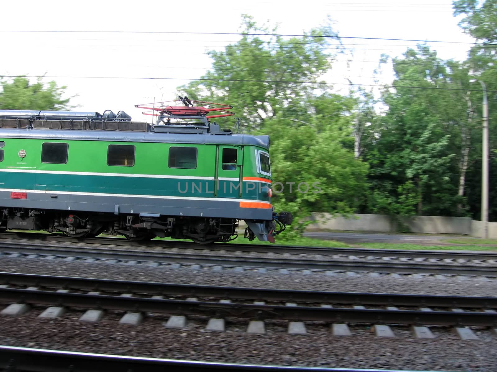 Green fast Russian locomotive moves through wood