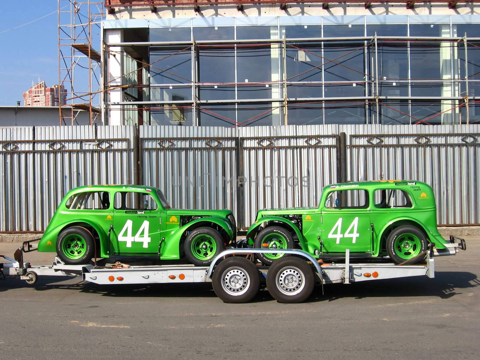 Two green racing cars at the trailer