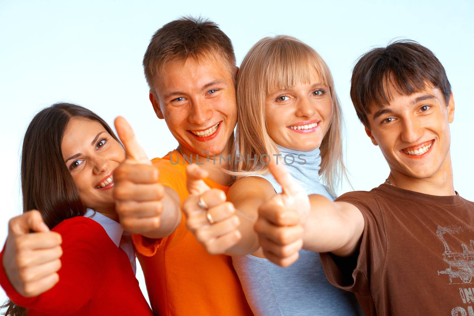 Four young people on white background laughing and giving the thumbs-up sign. 
