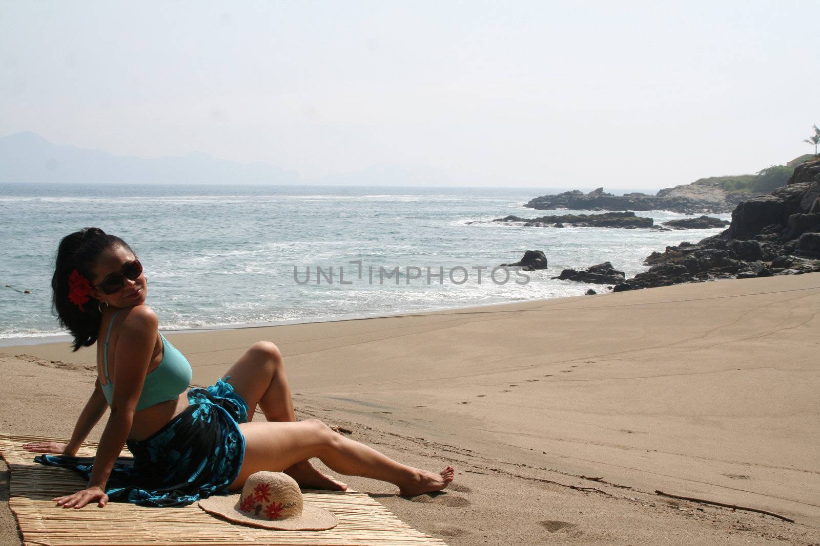 Young Latin woman sitting on beach