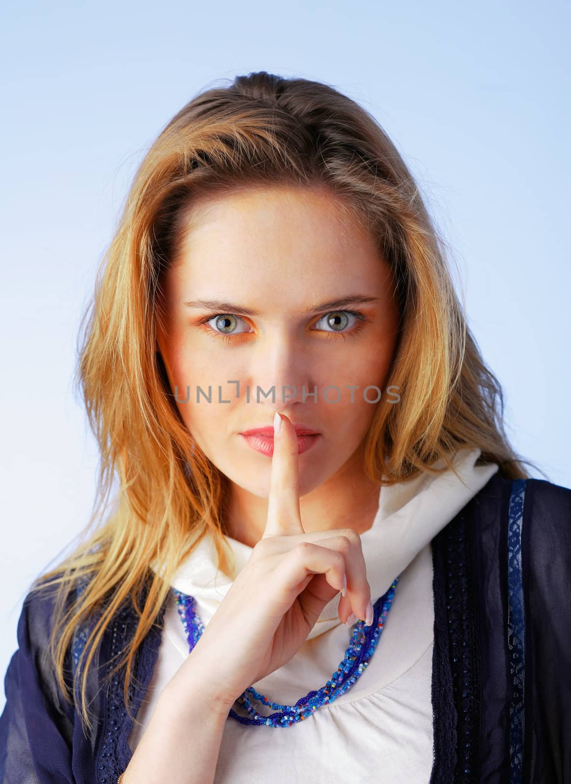 Beautiful young woman with her finger to her lips for silence.