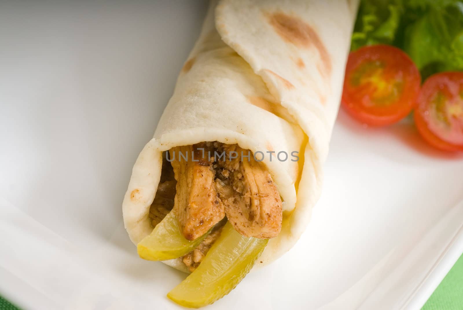 pita bread chicken roll with pickles cucumbers on a plate with pachino tomatoes and lettuce
