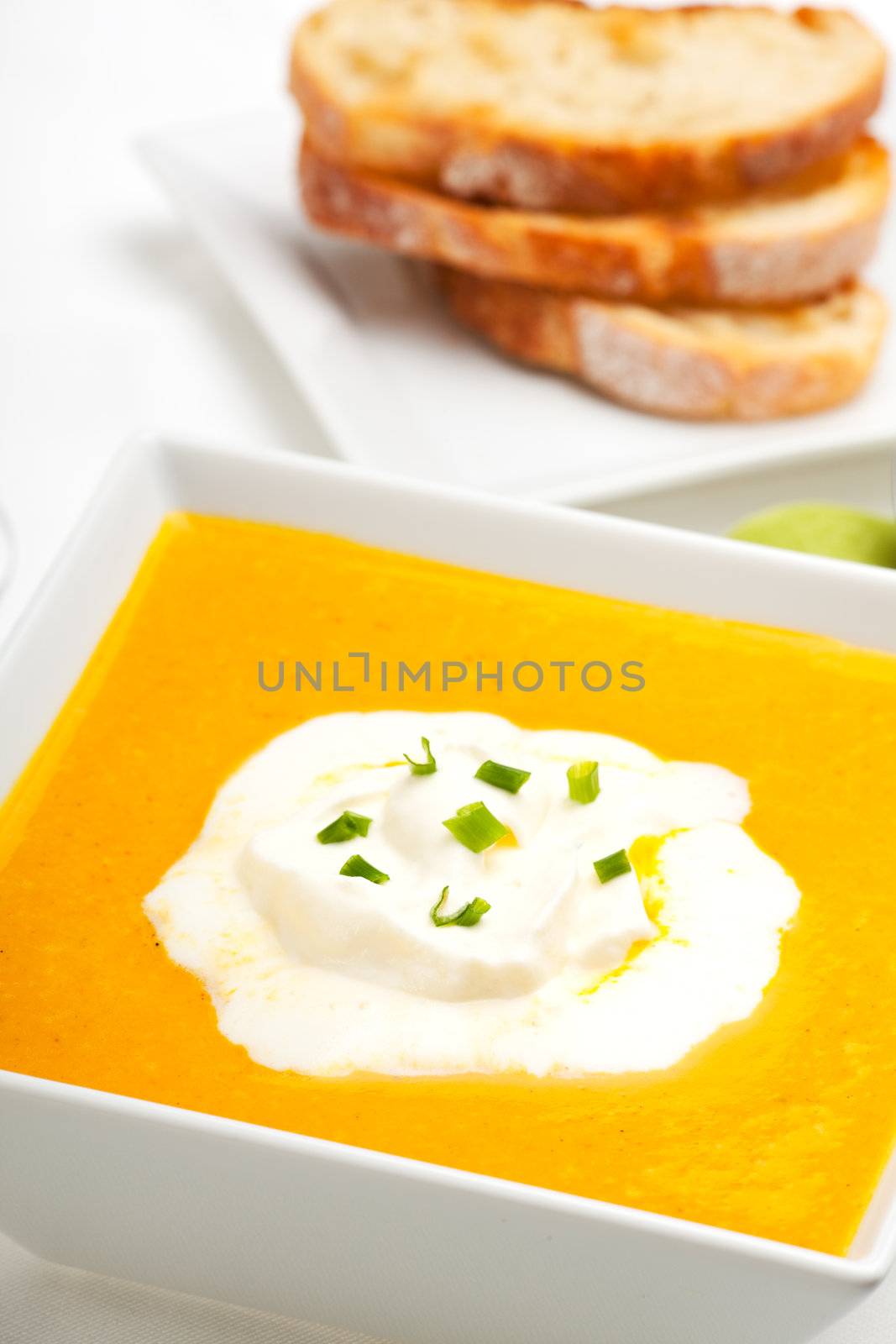 pumpkin soup and baguette isolated on white
