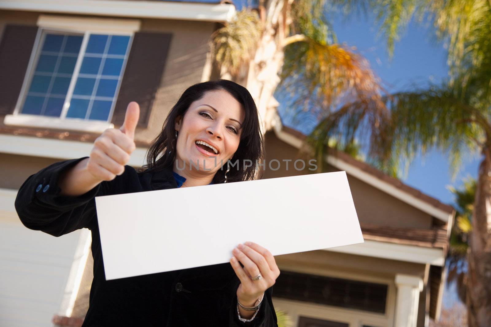 Happy Attractive Hispanic Woman with Thumbs Up Holding Blank Sign in Front of House.