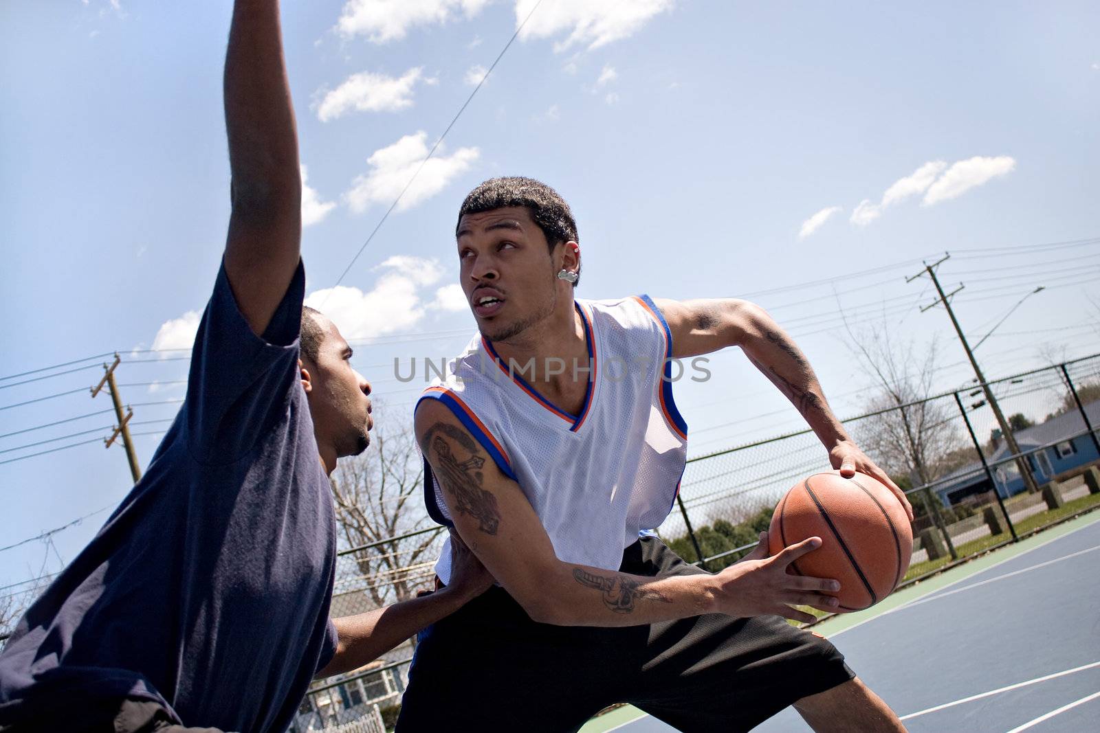 A young basketball player guarding his fierce opponent.