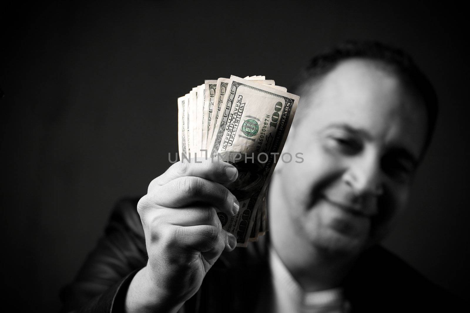 A happy man holds a handful of cash with selective color.