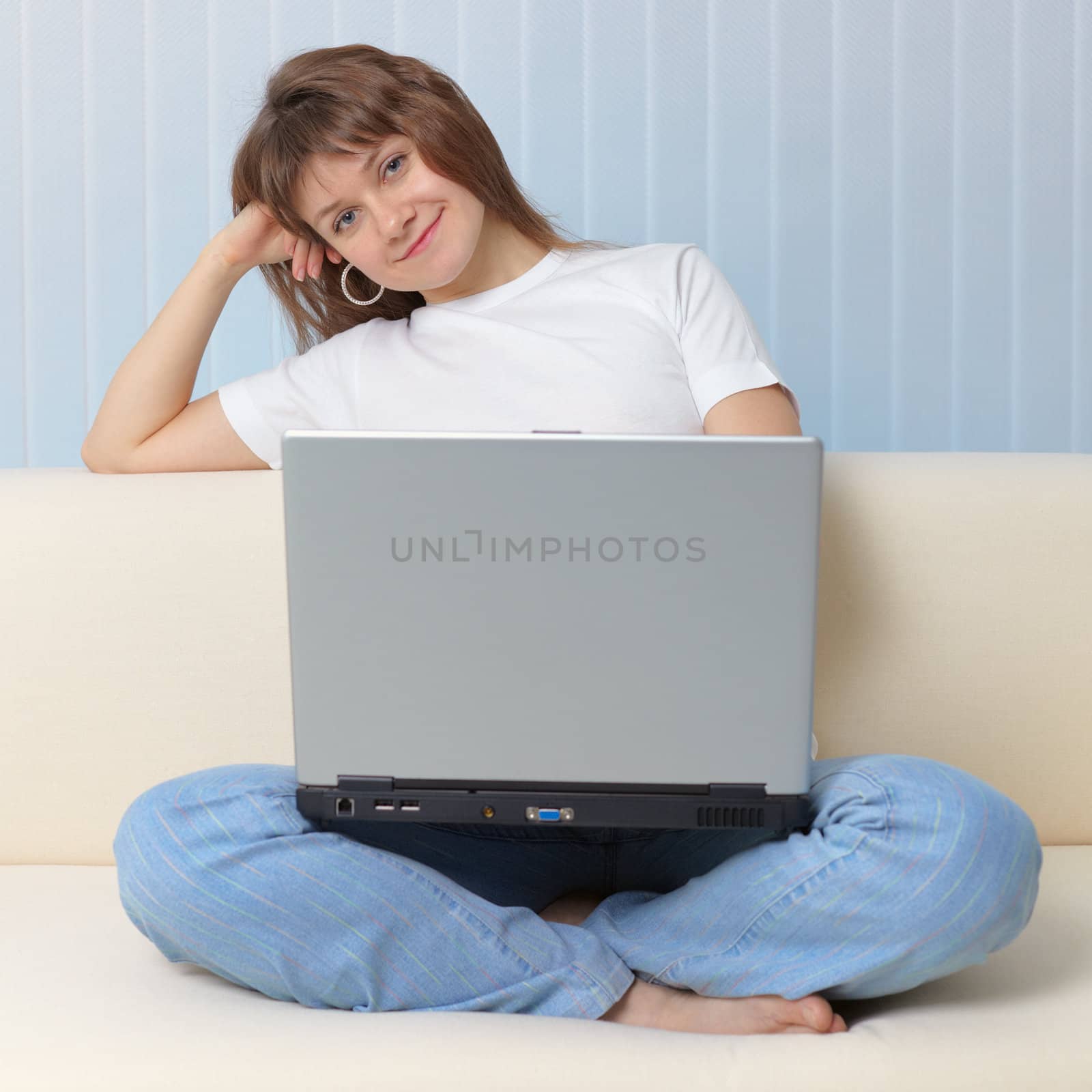 Beautiful young girl with laptop has rest sitting on a sofa by pzaxe