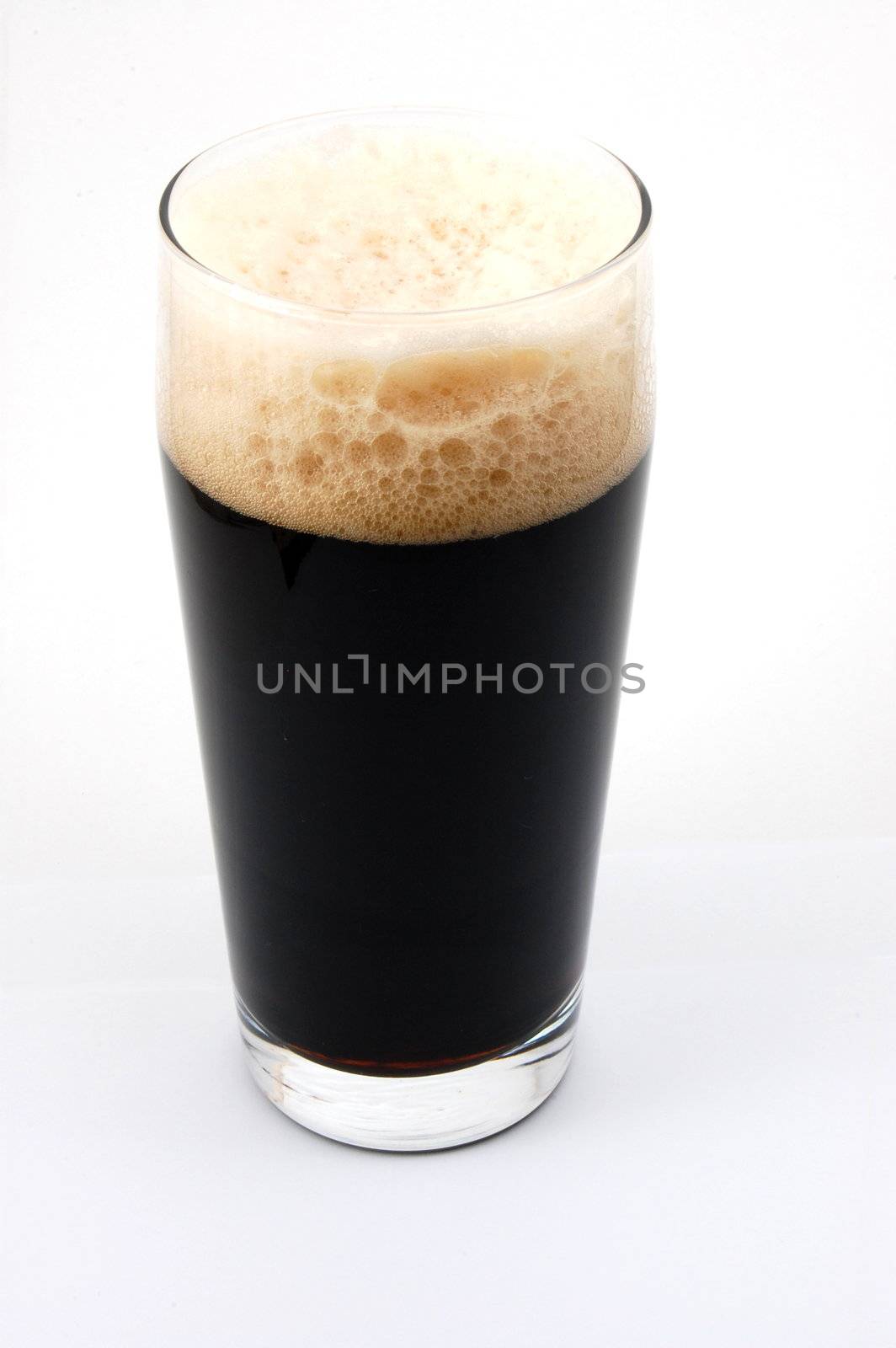 dark beer isolated on white background with foam