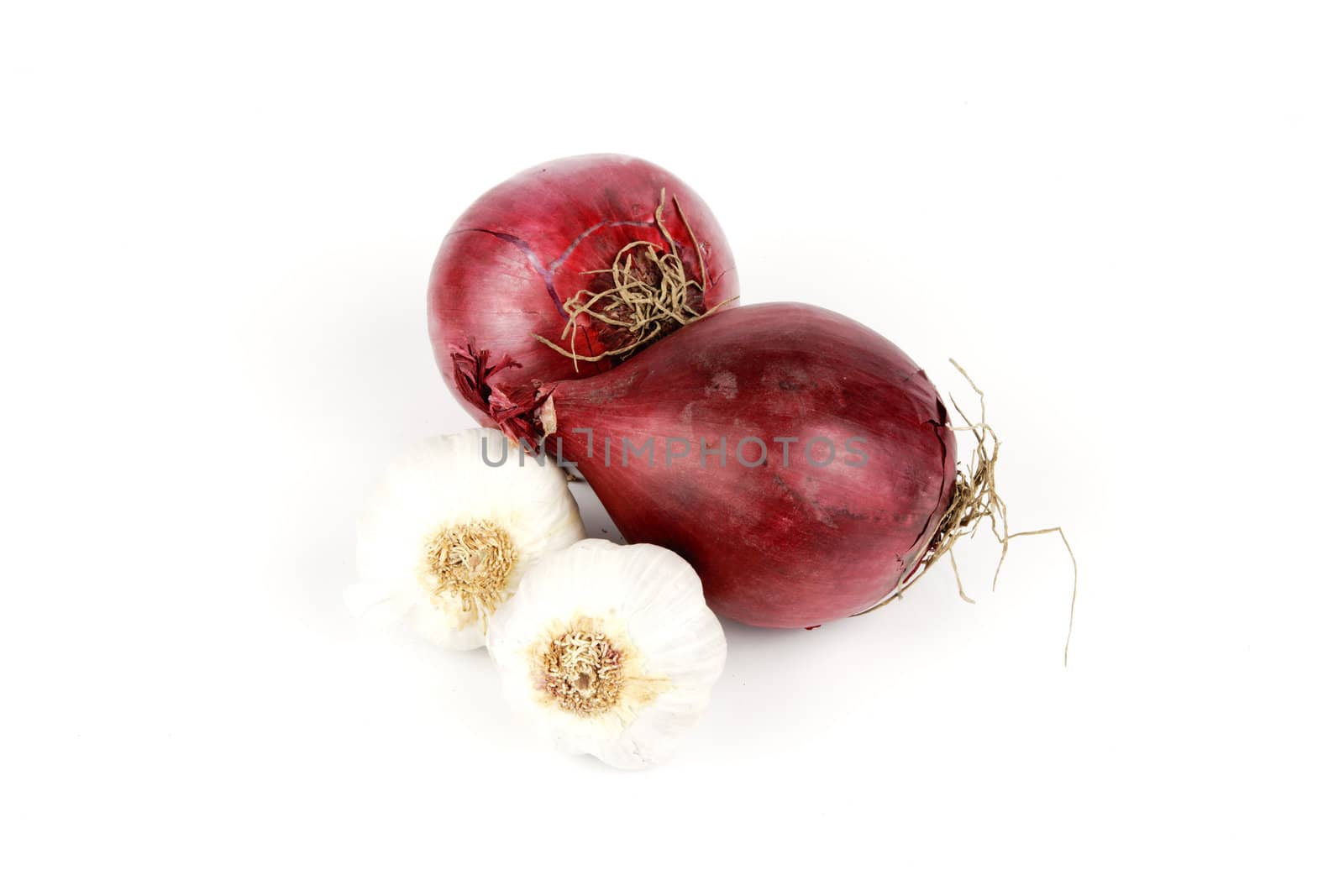 Two raw unpeeled red onions and two bulbs of garlic on a reflective white backgrounds