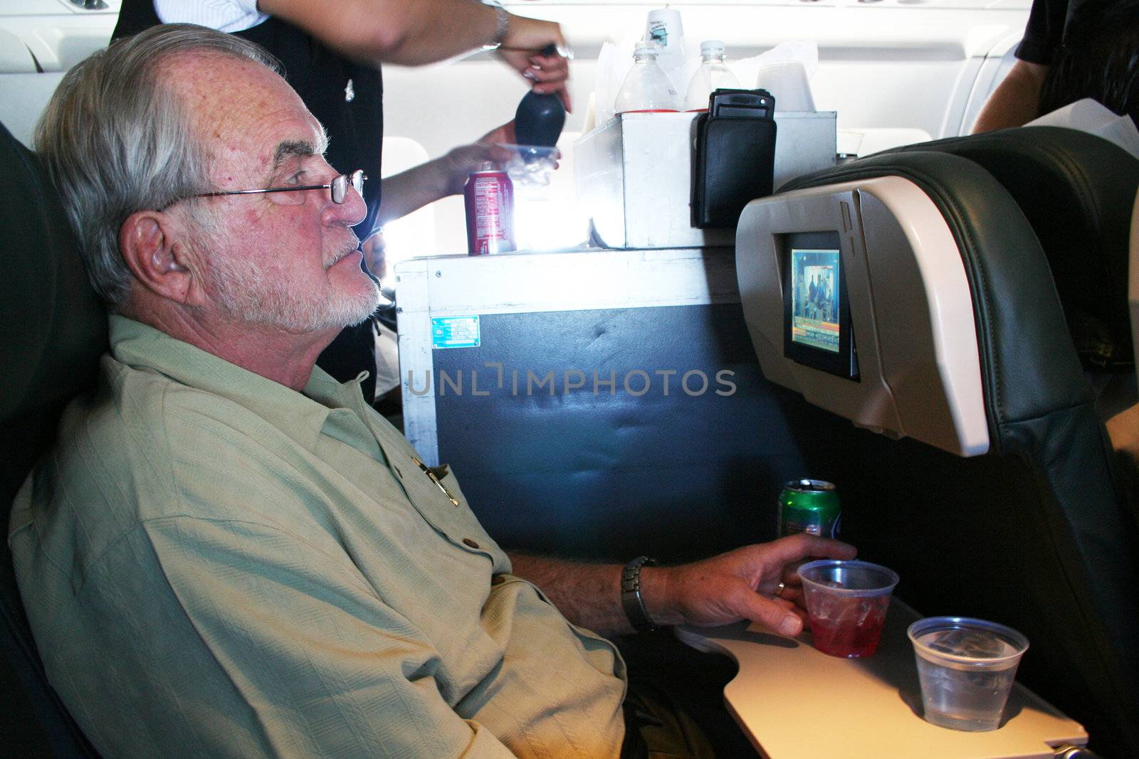 Man on airplane with stuartess serving drinks