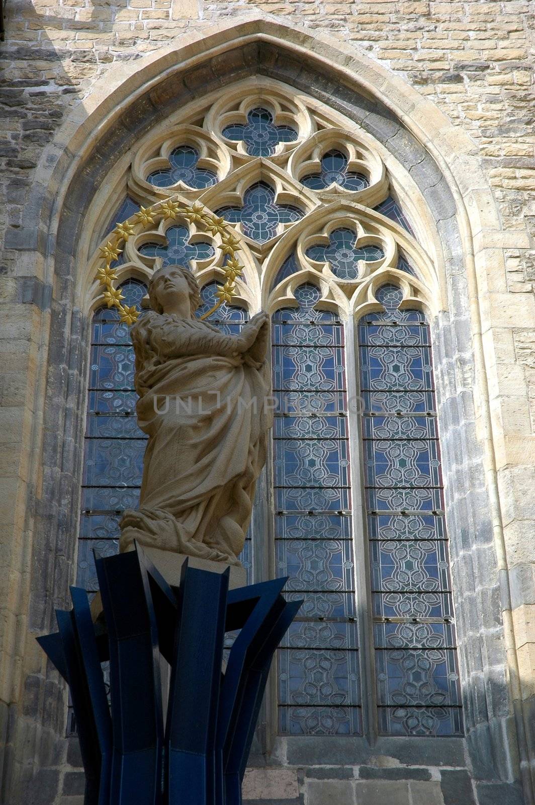 Stained glass window of a church in Prague and a statue of saint next to it. 