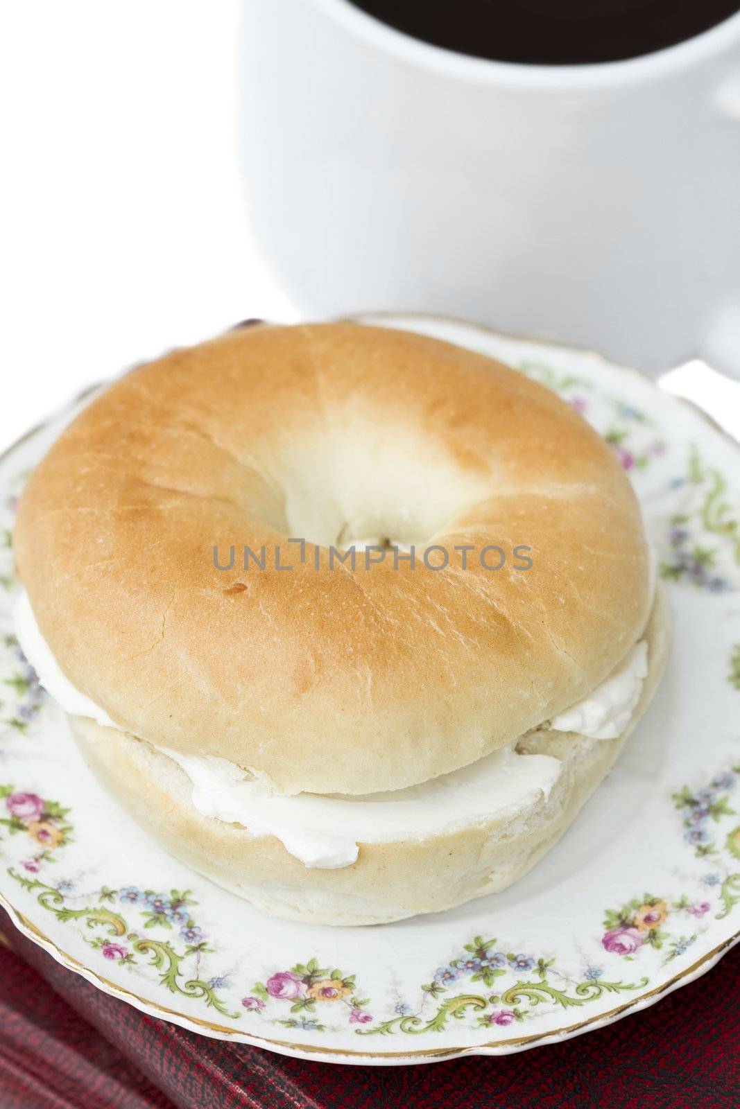 Bagel and coffee isolated on white. Bagel is sitting on top of old books. Shallow DOF. 
