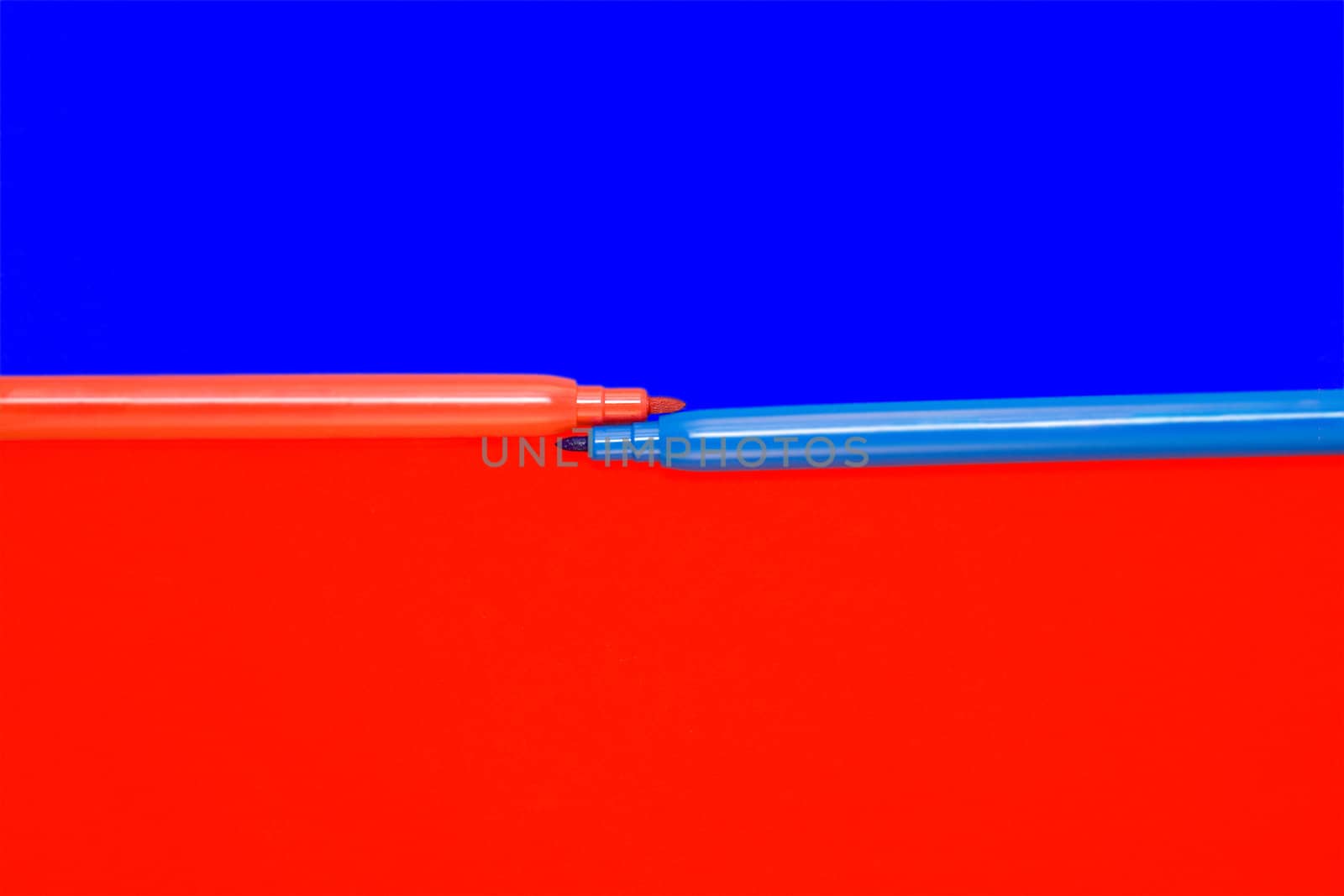Red and blue felt-tip pens lay on a color background