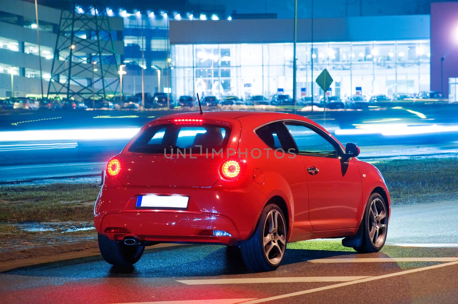Side view of red car in the city, near the airport at night, Riga, Latvia