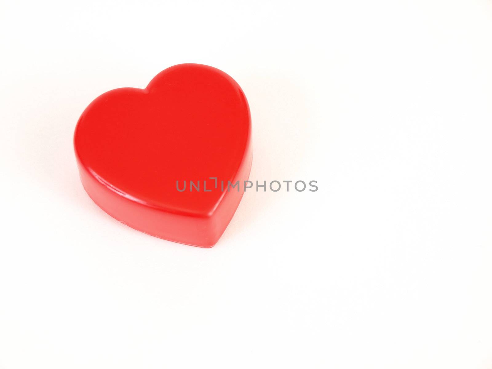 A plastic red heart shape on a white background with room for text.