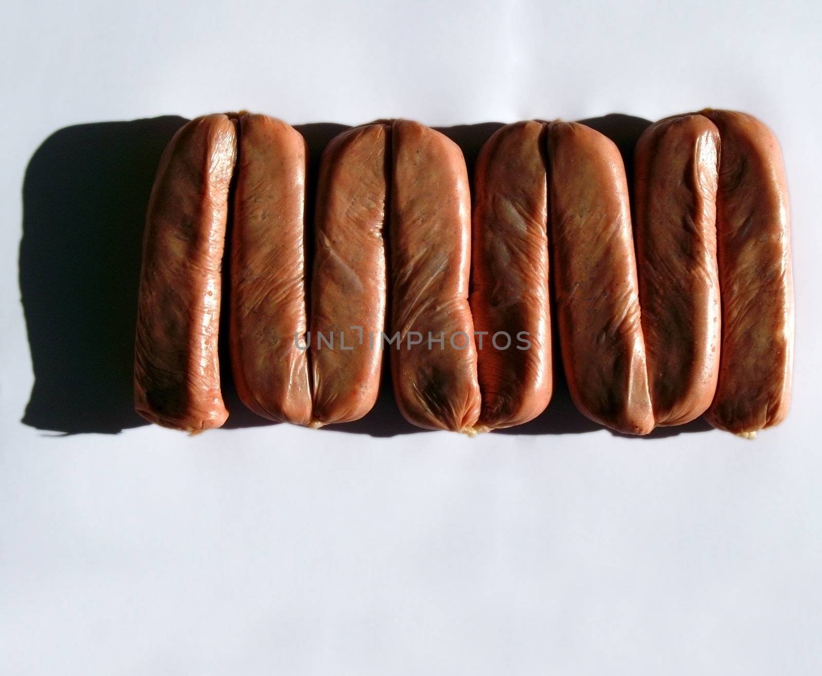 Eight uncooked link sausages in appropriate raw, harsh light. With copyspace