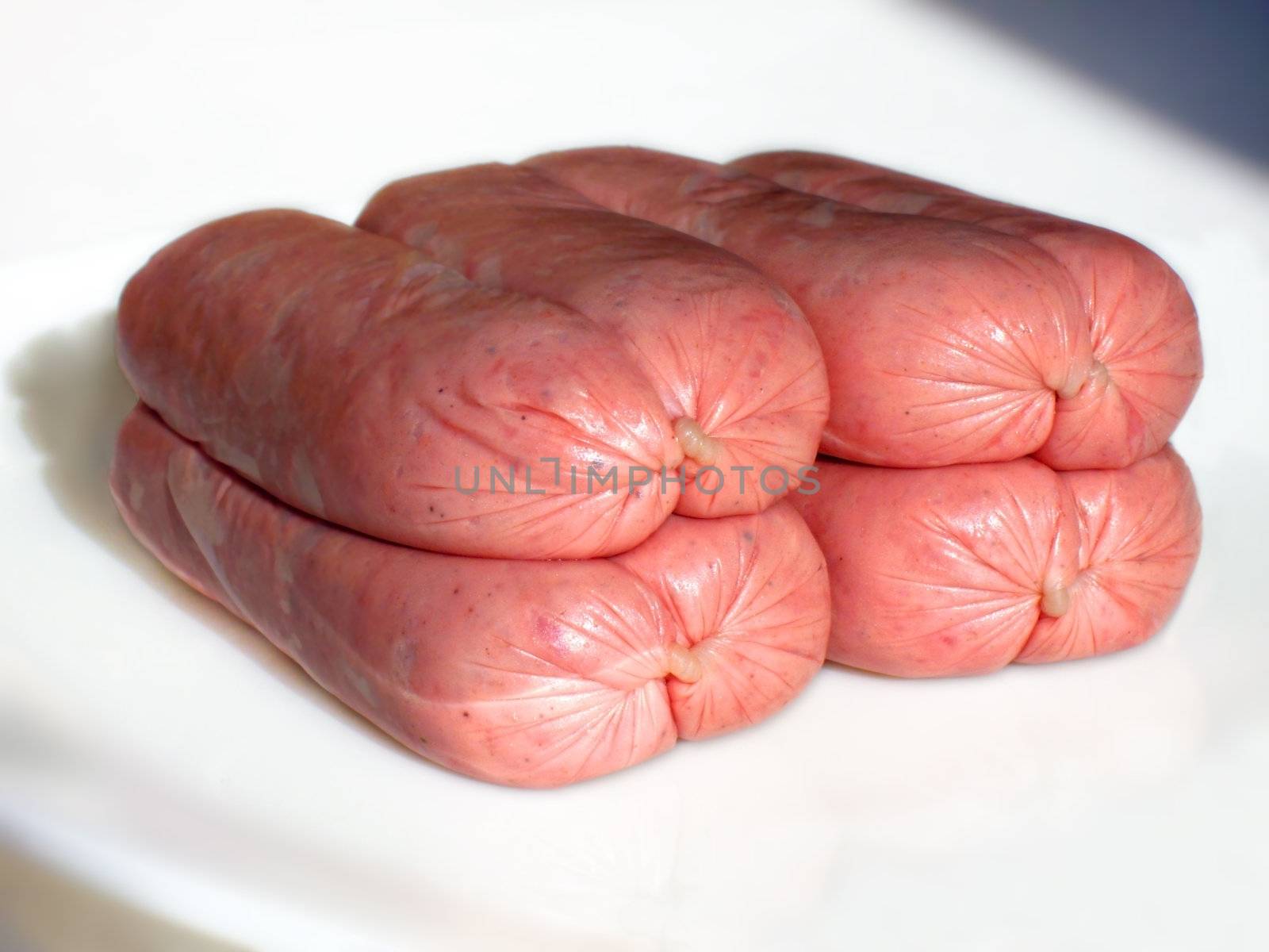Eight uncooked linked sausages on a plate