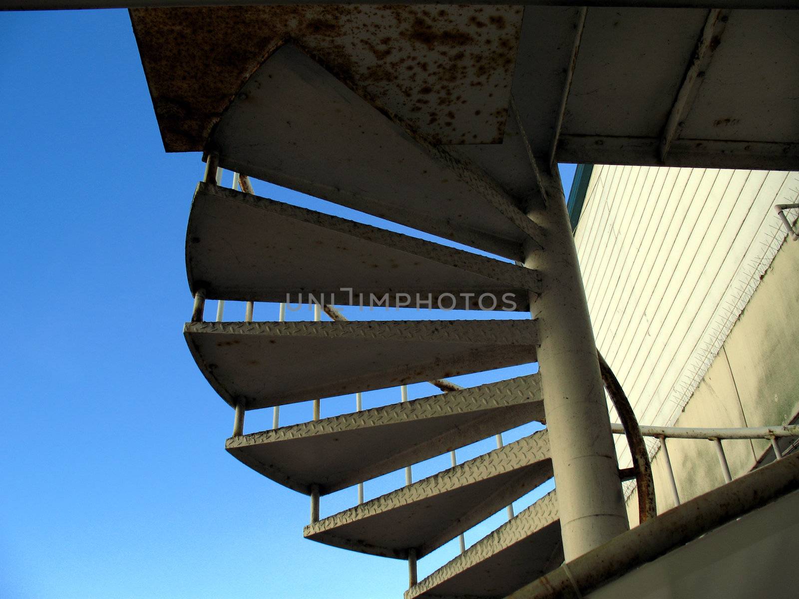 Spiral staircase slightly silhouetted against a blue summer sky