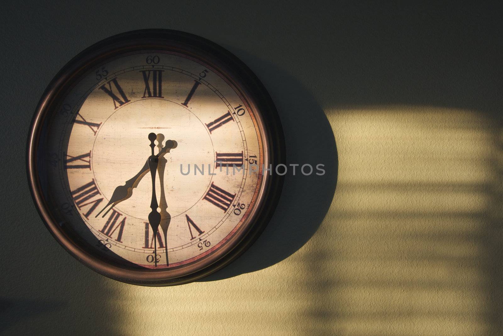 Antique Clock on an olive green wall with dramatic evening light and shadows.