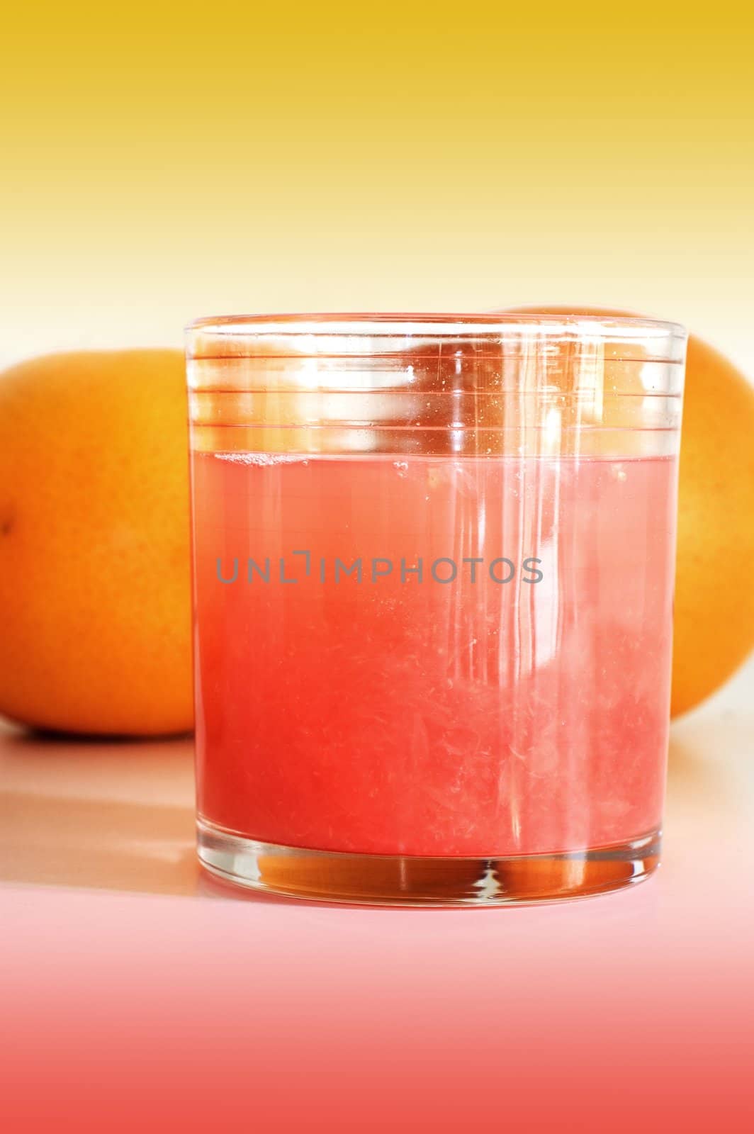 Grapefruit juice in glass with grapefruits in the background 