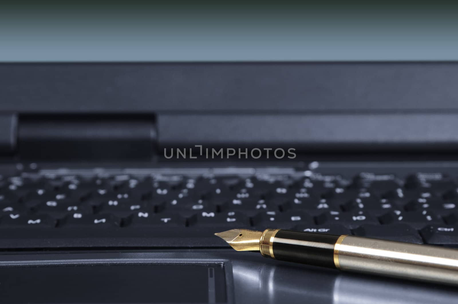 gold feather pen on the keyboard of the personal computer.