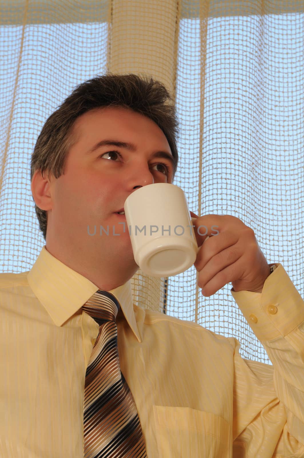 man in a tie on a background a window with a white cup