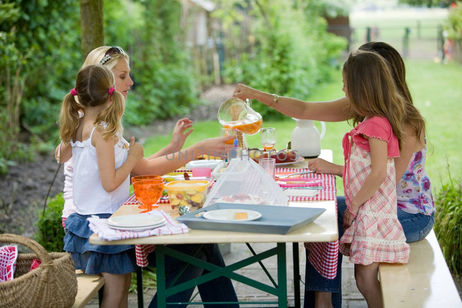 Two mothers with their daughters enjoying an outdoors picnic