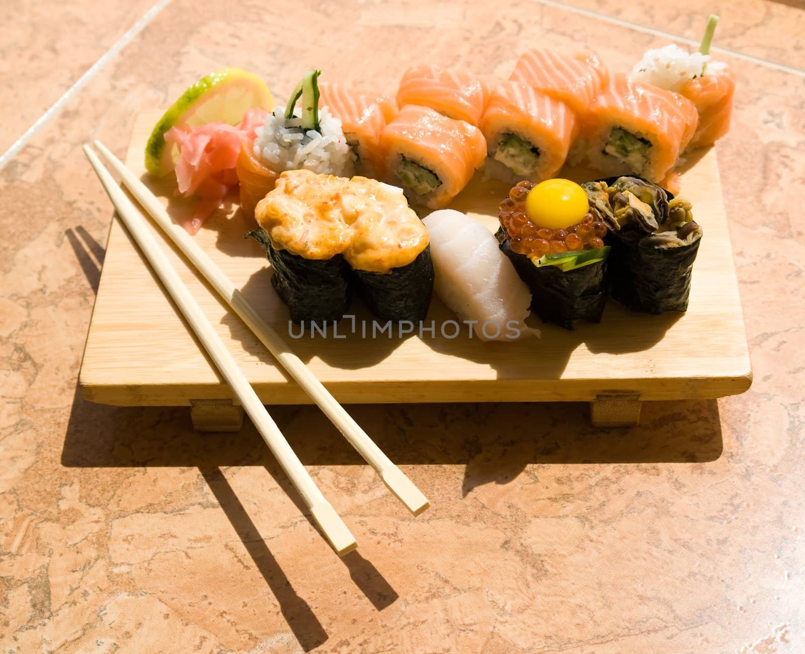 Various sushi. Traditional wooden plate and chopsticks.