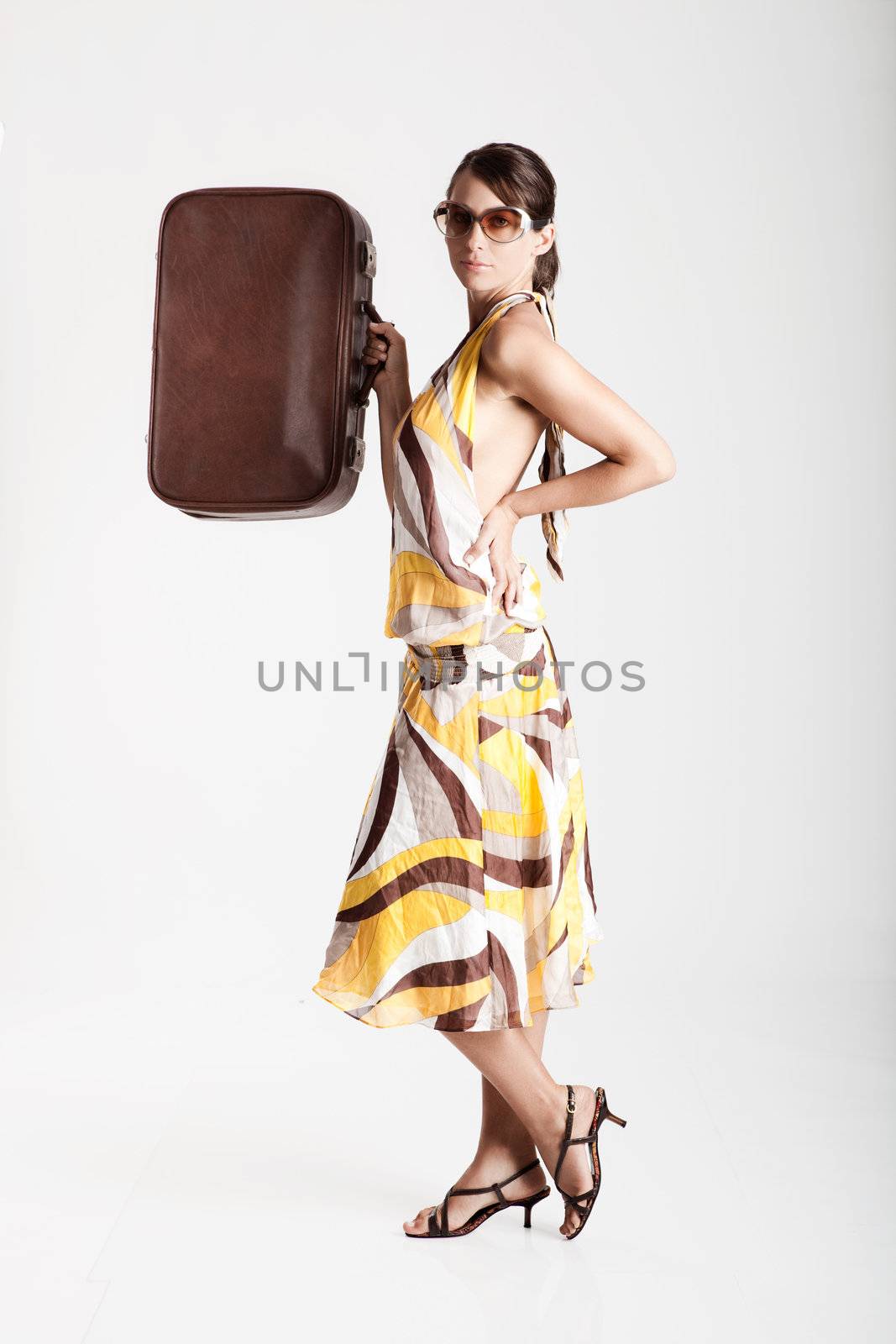 Beautiful fashion woman posing with a vintage suitcase