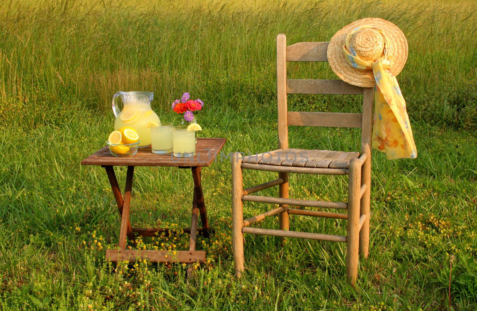 lemonade, fresh flowers and empty chair with a womans hat all outside on a beautiful summers day.