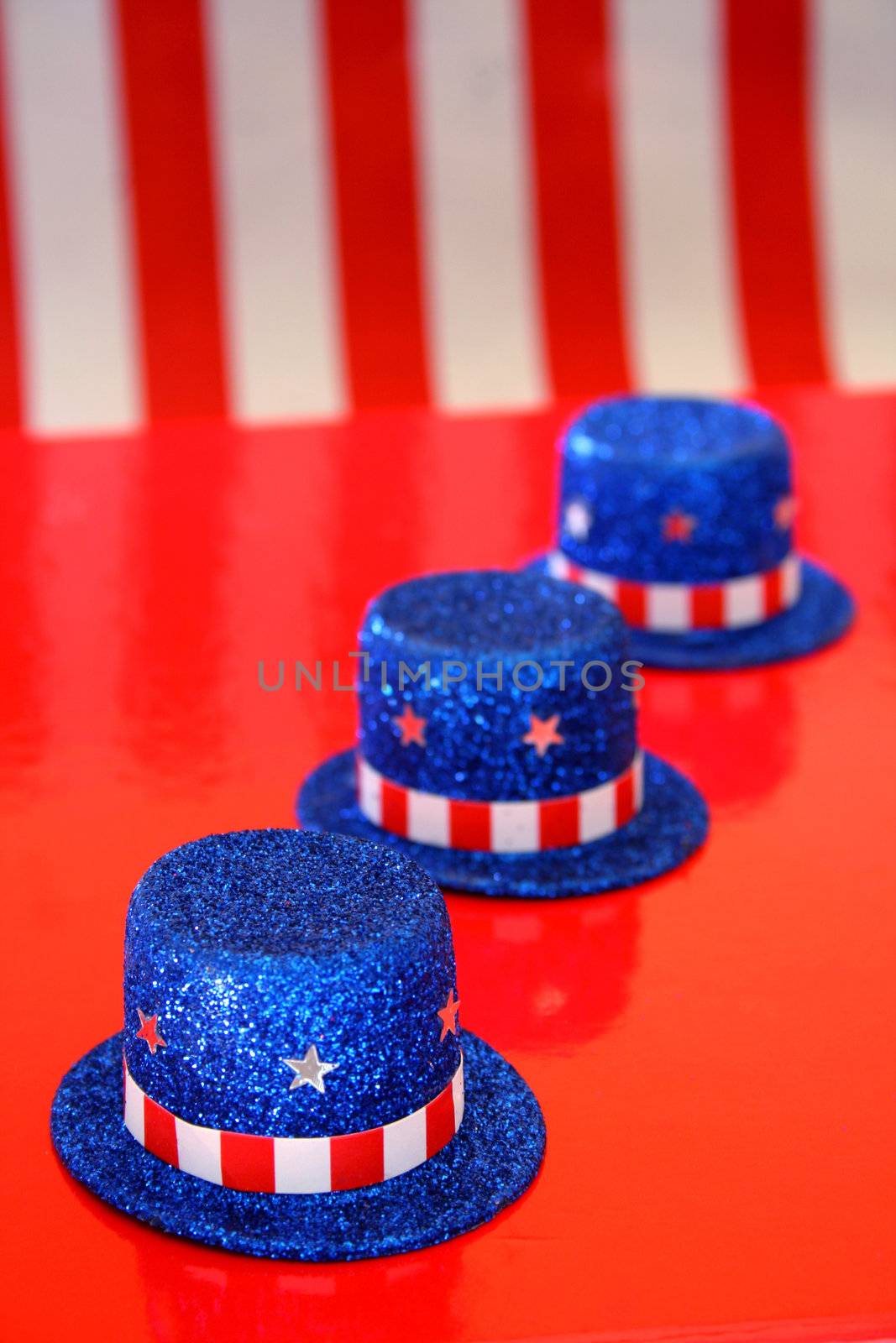 Three top hats with fourth of July theme on a red background.


