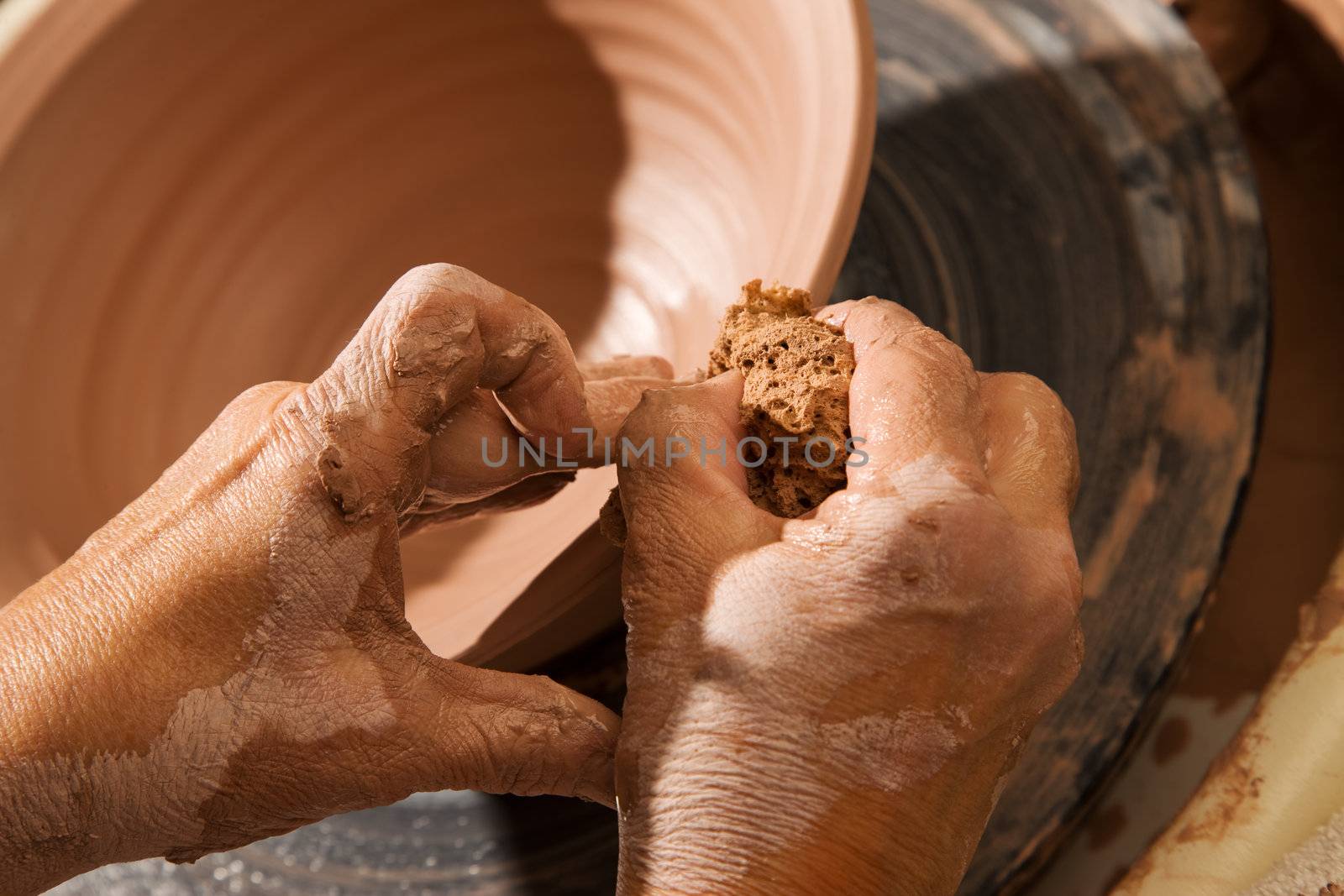 Hands forming clay pot on pottery wheel