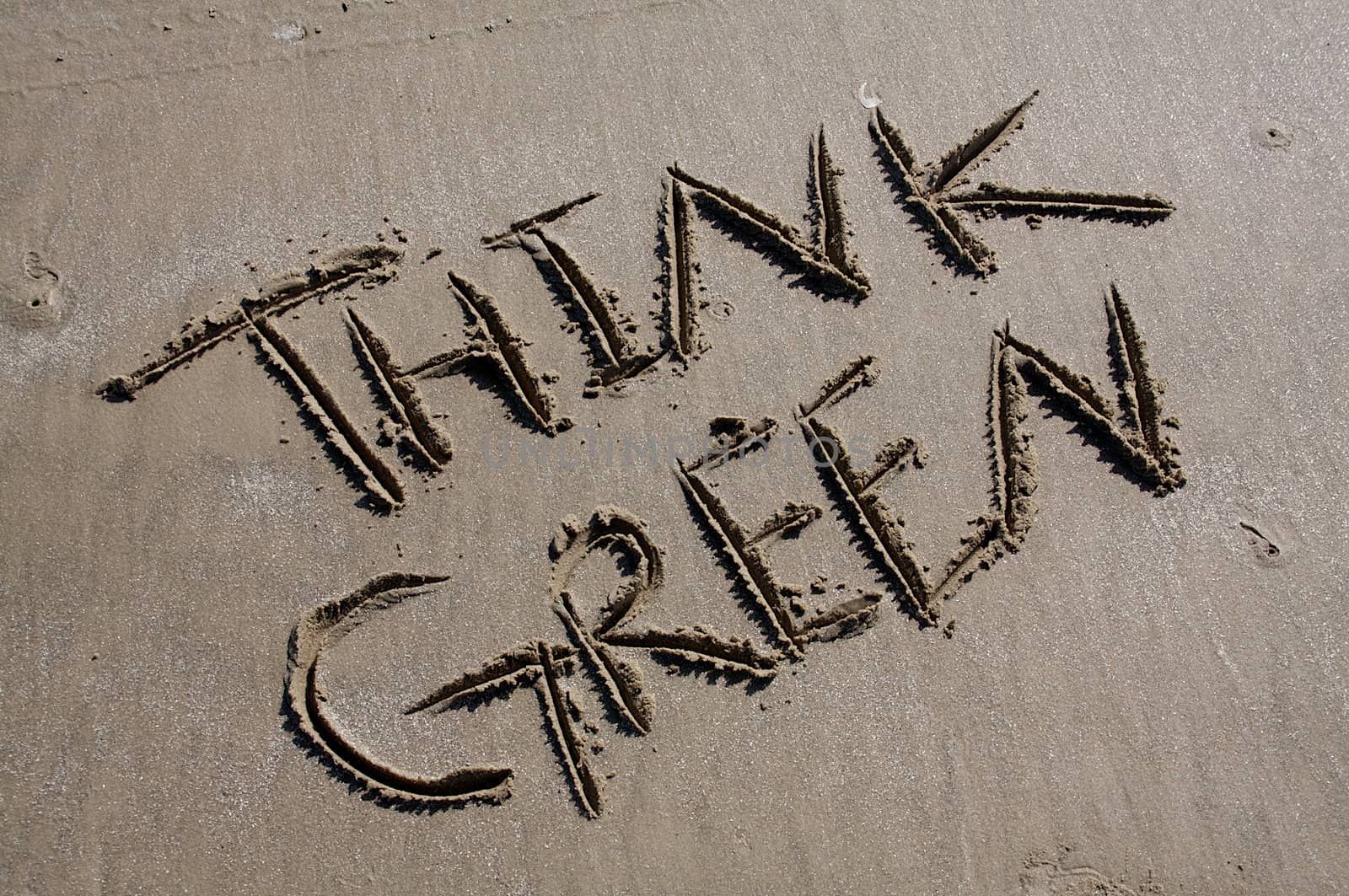 The words "Think Green" are carved into a sandy beach