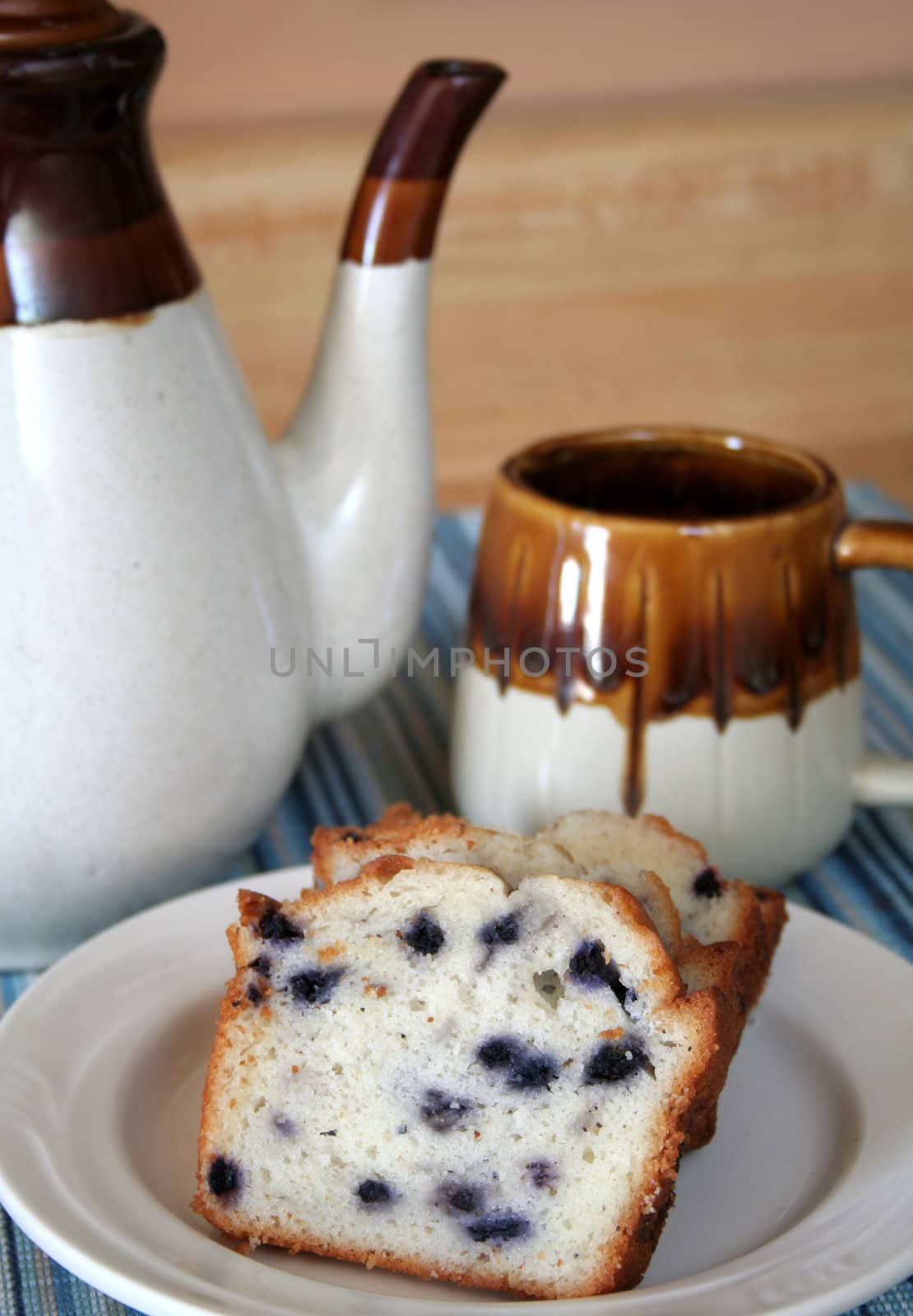 plate of blueberry cake with coffee cup and coffee pot.
