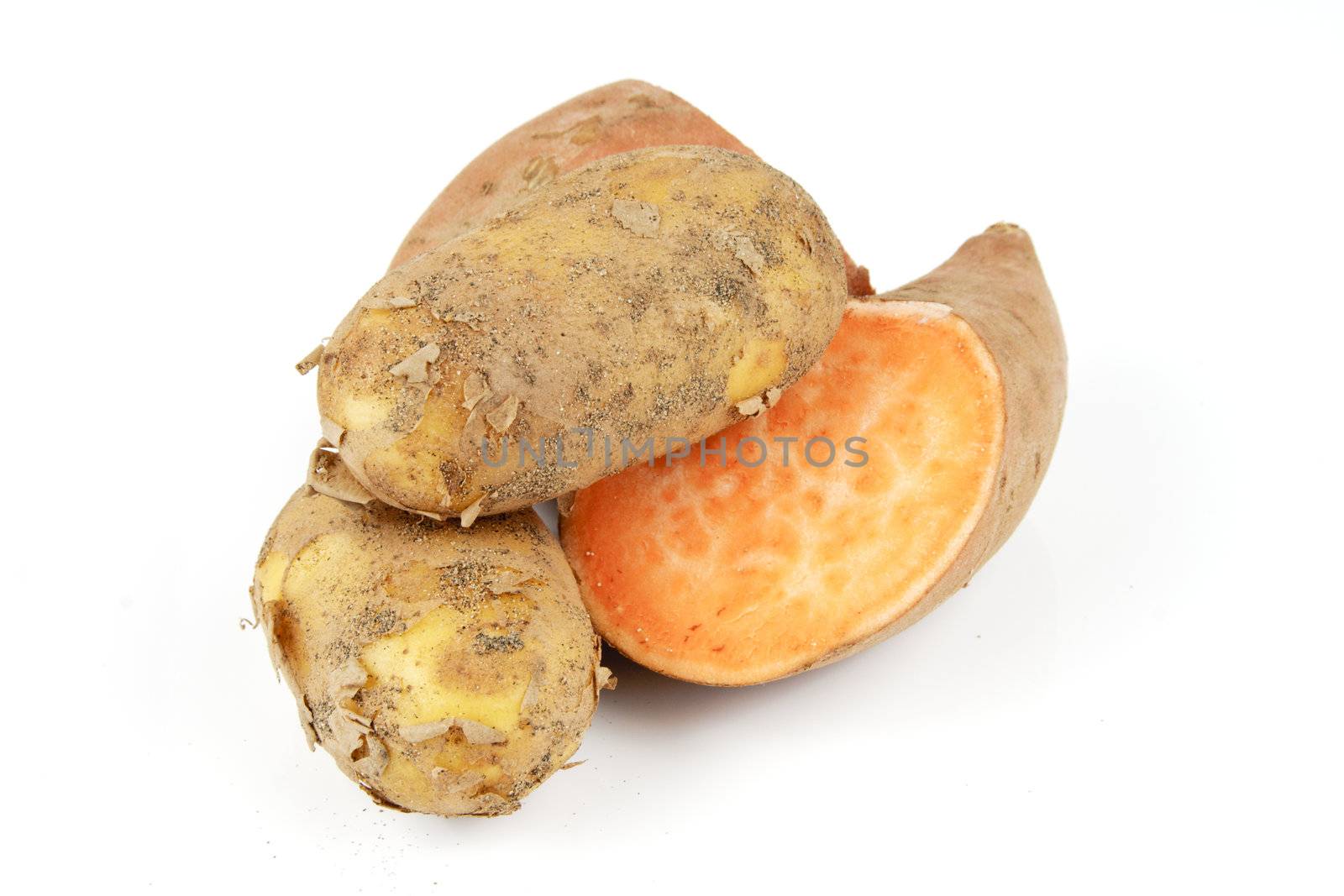 Sweet Potato cut in half with a small brown potato on a reflective white background