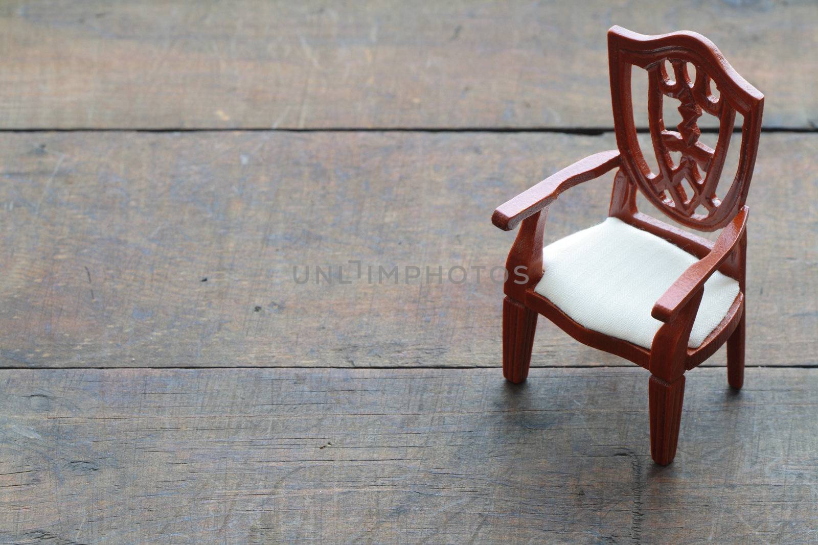 Toy wooden chair standing on wooden background with copy space