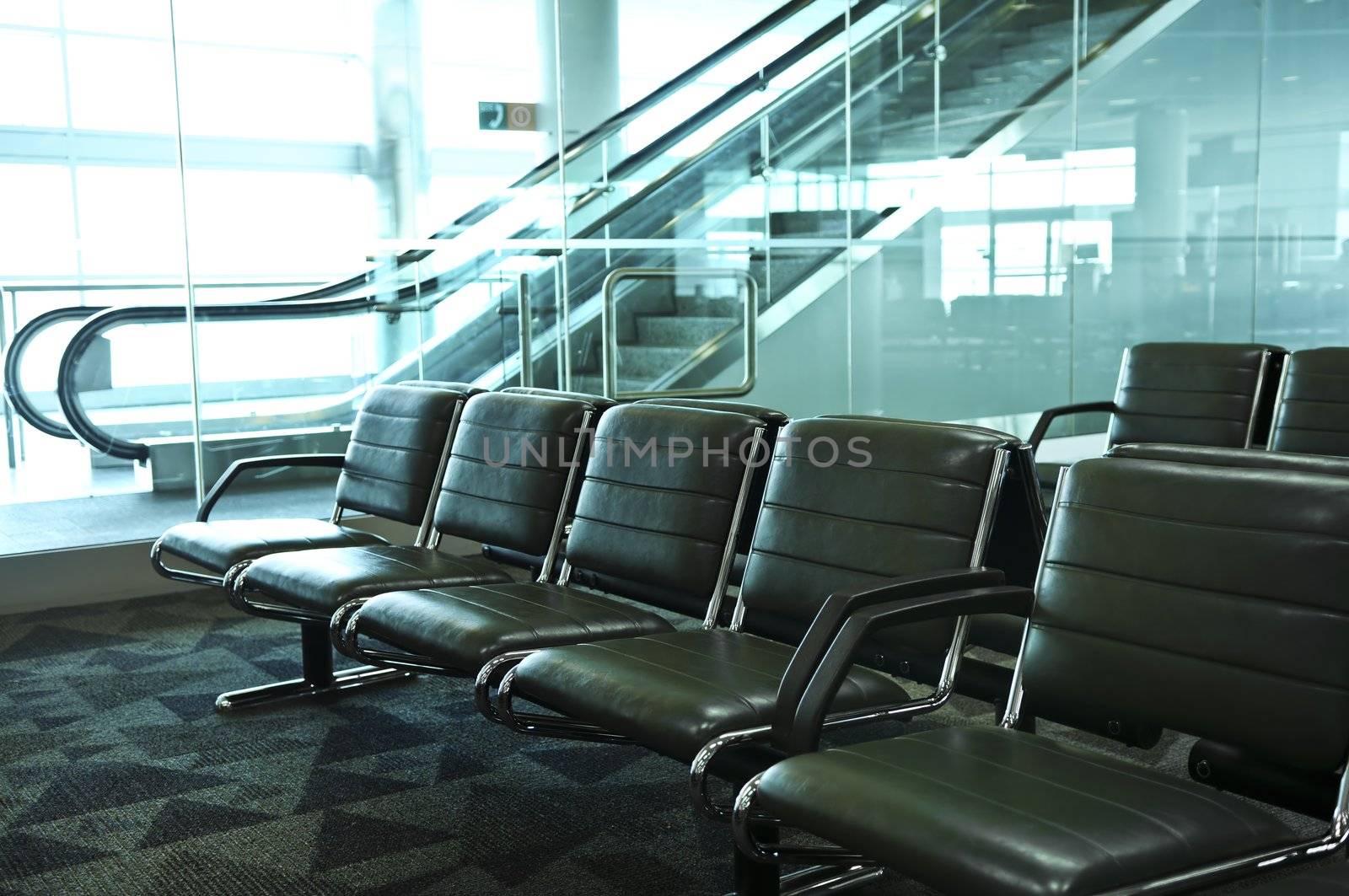 Row of chairs and escalator inside an airport